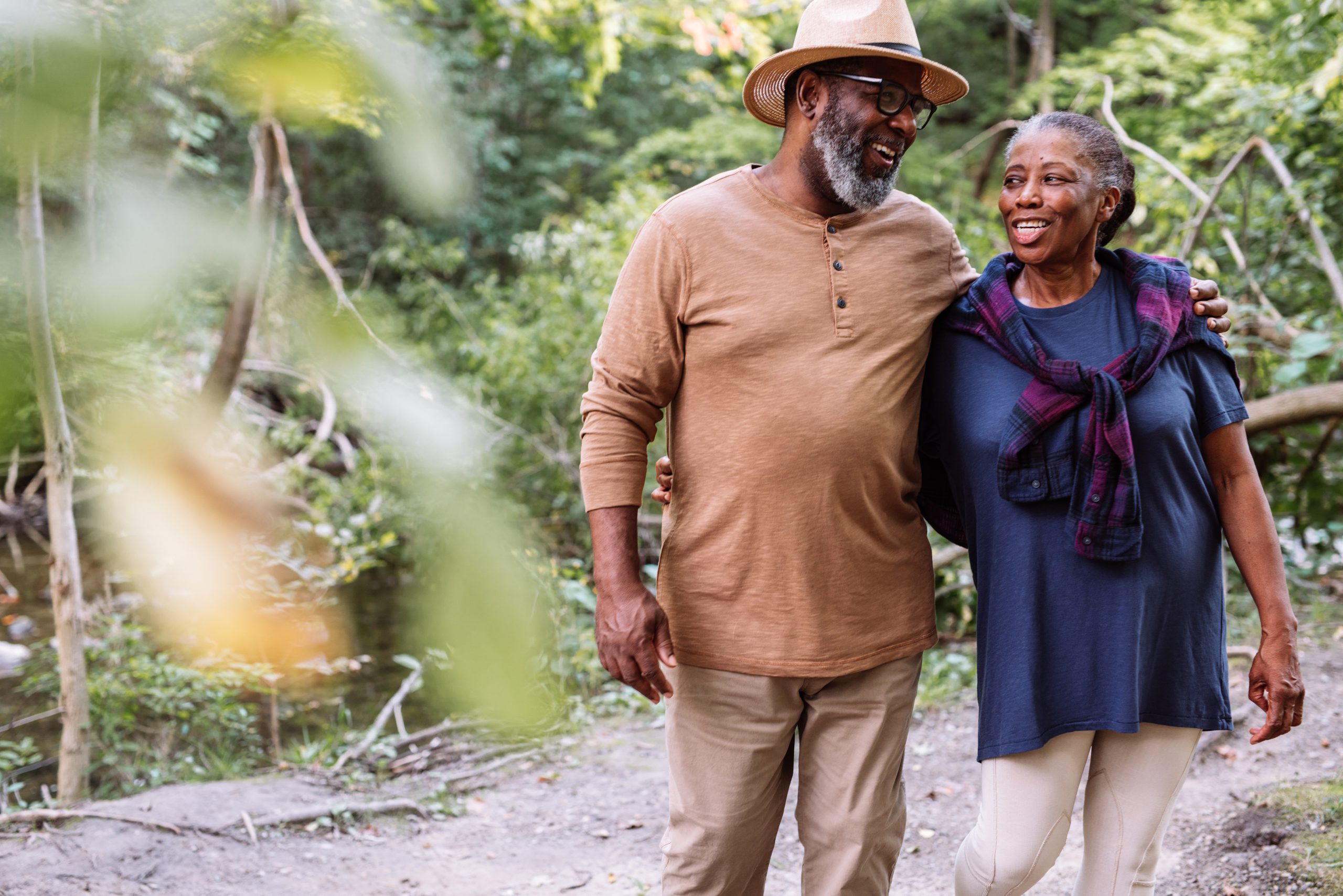 Two adults walking close together amidst plants.